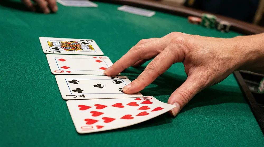 Real playing cards arranged in alternating red and black cascade on casino felt